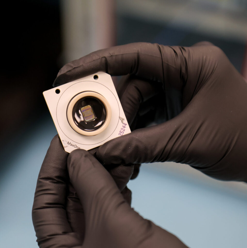 Gloved hands hold a computer chip.