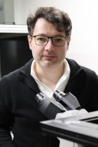 Ali Yanik in a black sweater and white shirt in his lab.