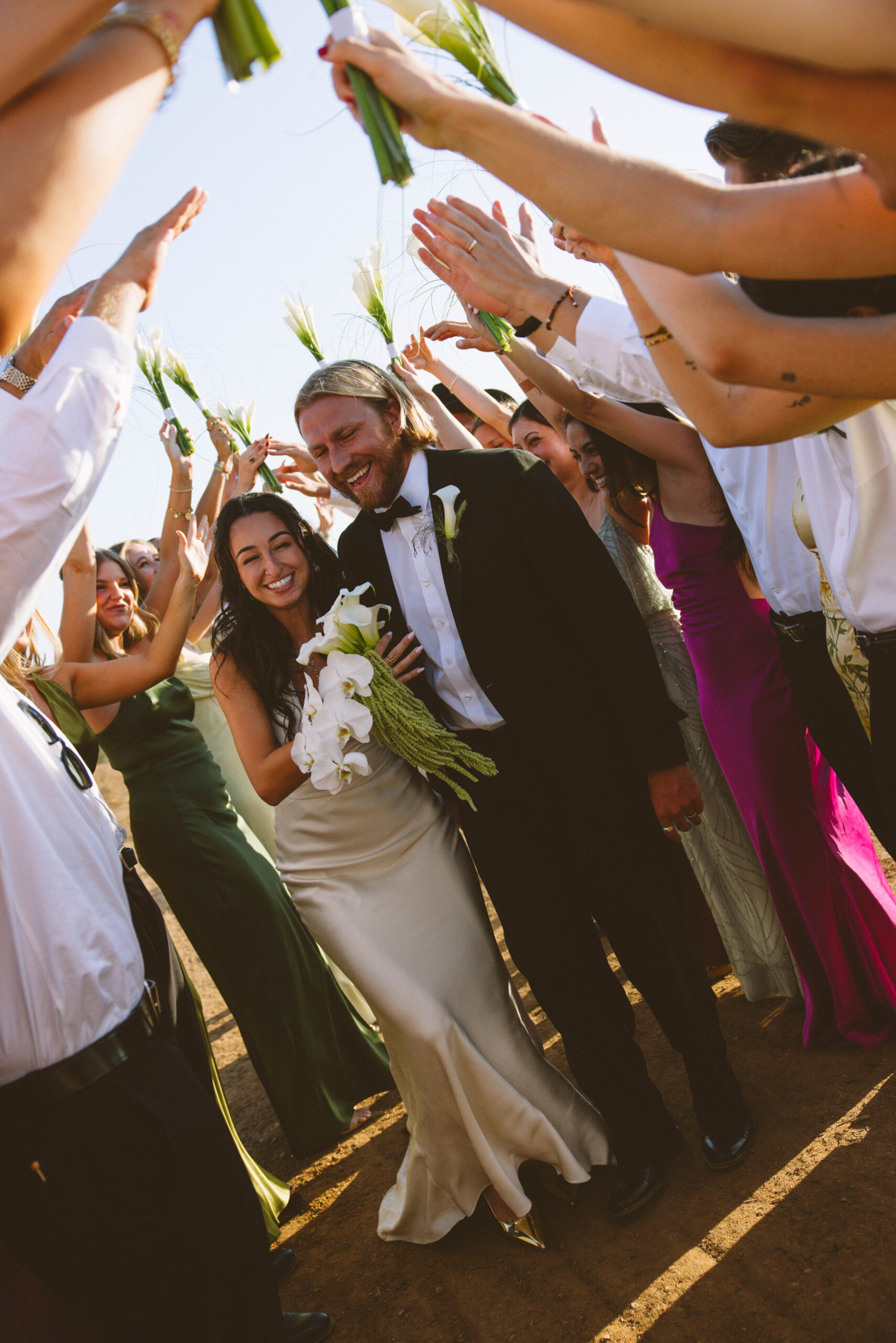 Bride and groom stand amongst attendees celebrating their wedding.