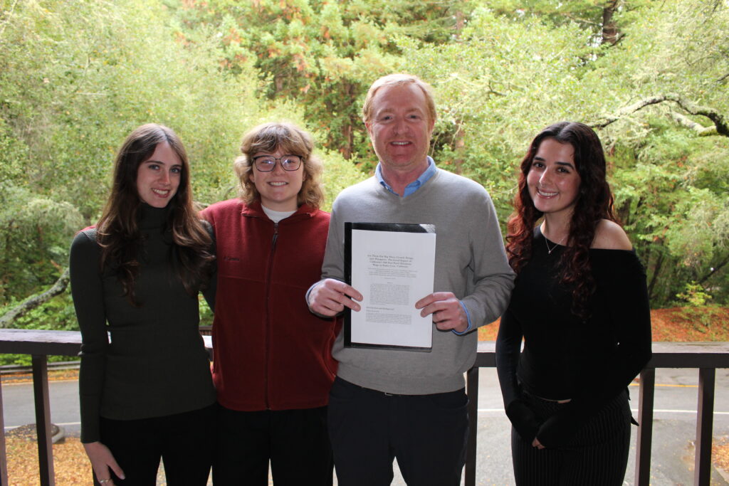 Three students and professor smile at camera