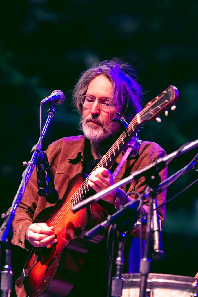 David Rawlings, Gillian Welch, and Paul Kowert playing instruments on stage.