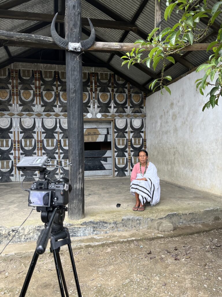 Village elder sitting in front of camera