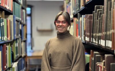 Sarah Steele standing between library shelves full of books