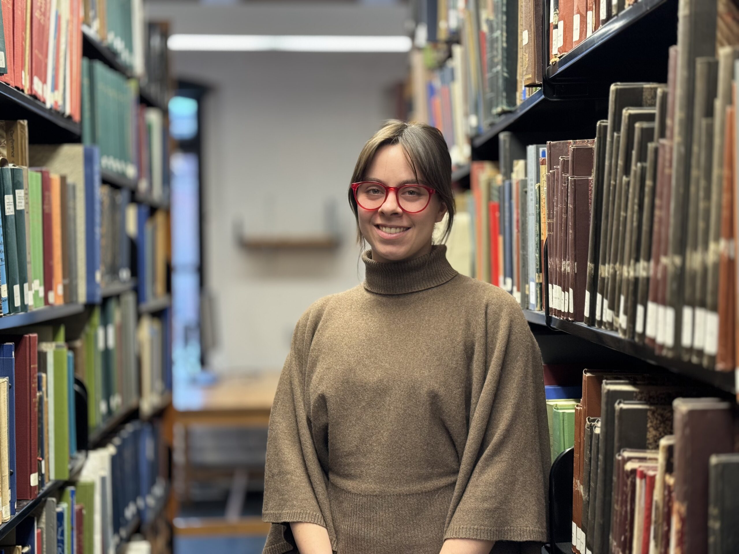 Sarah Steele standing between library shelves full of books