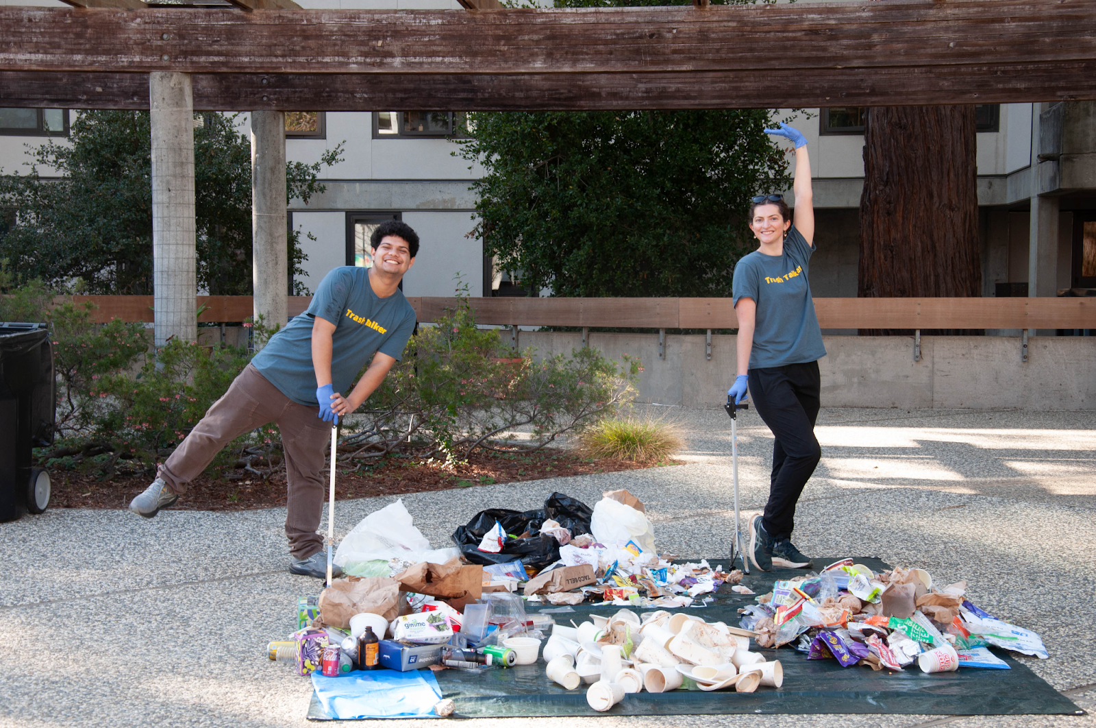 Two student workers in front of a pile of trash