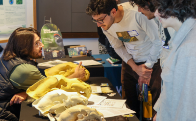 A man talking to students visiting a table that is displaying bear skulls
