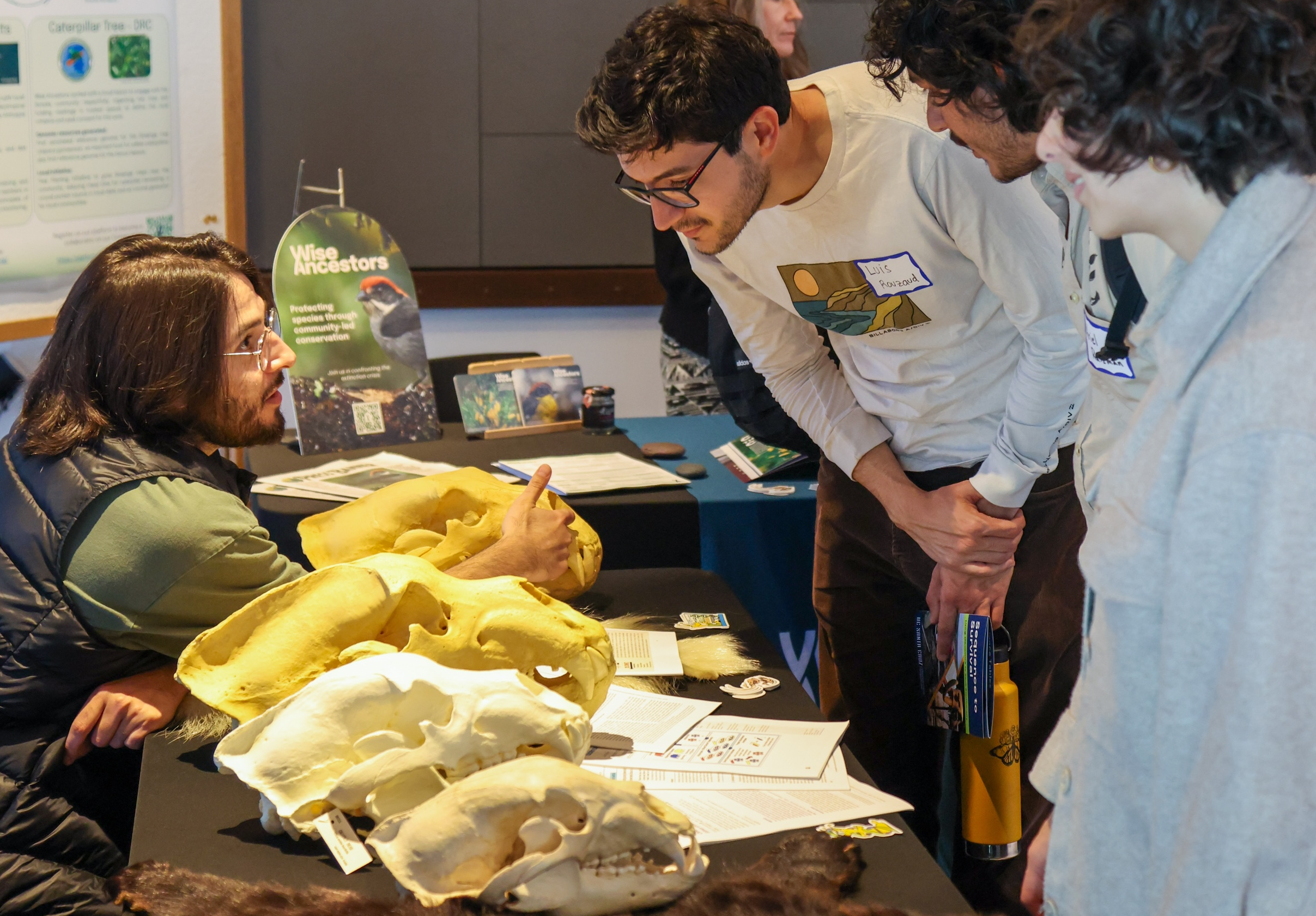 A man talking to students visiting a table that is displaying bear skulls