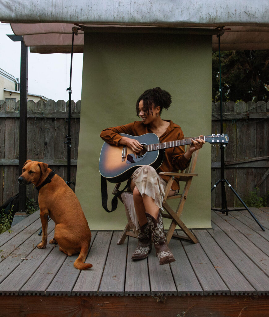 August Lee Stevens performs with guitar alongside her dog Clyde.