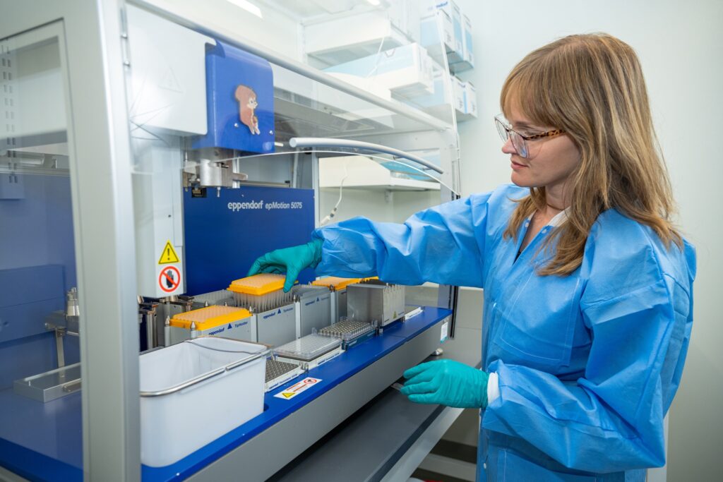 Young woman in lab gear handling equipment.