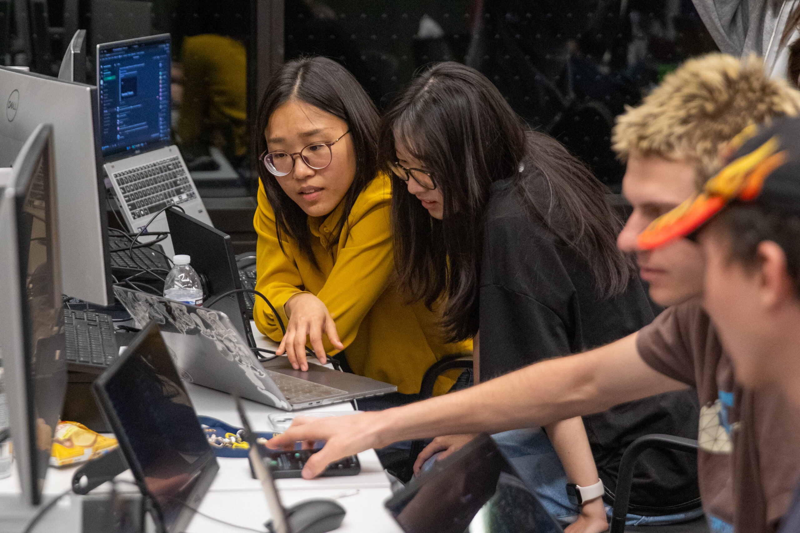 Two female-presenting students look with focus at a computer screen