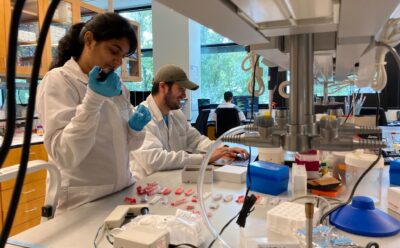 Two people in white lab coats work in the lab