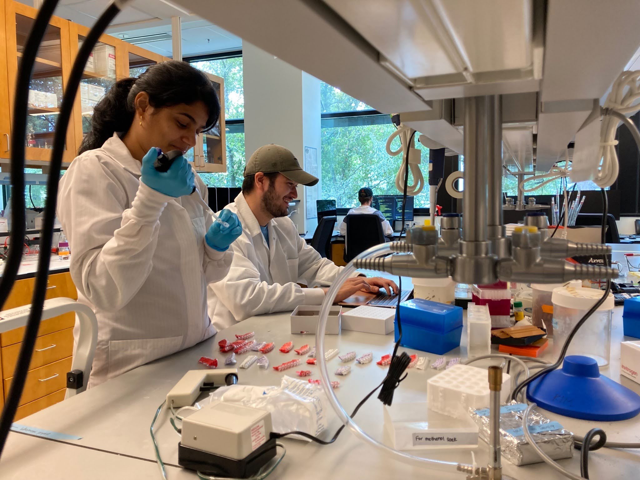Two people in white lab coats work in the lab