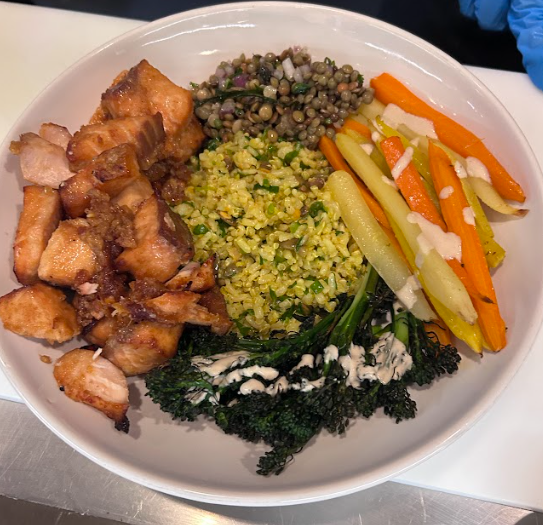 Close-up of a healthy and vibrant plated meal featuring salmon, broccolini, carrots, and Mediterranean lentil salad on a white plate.