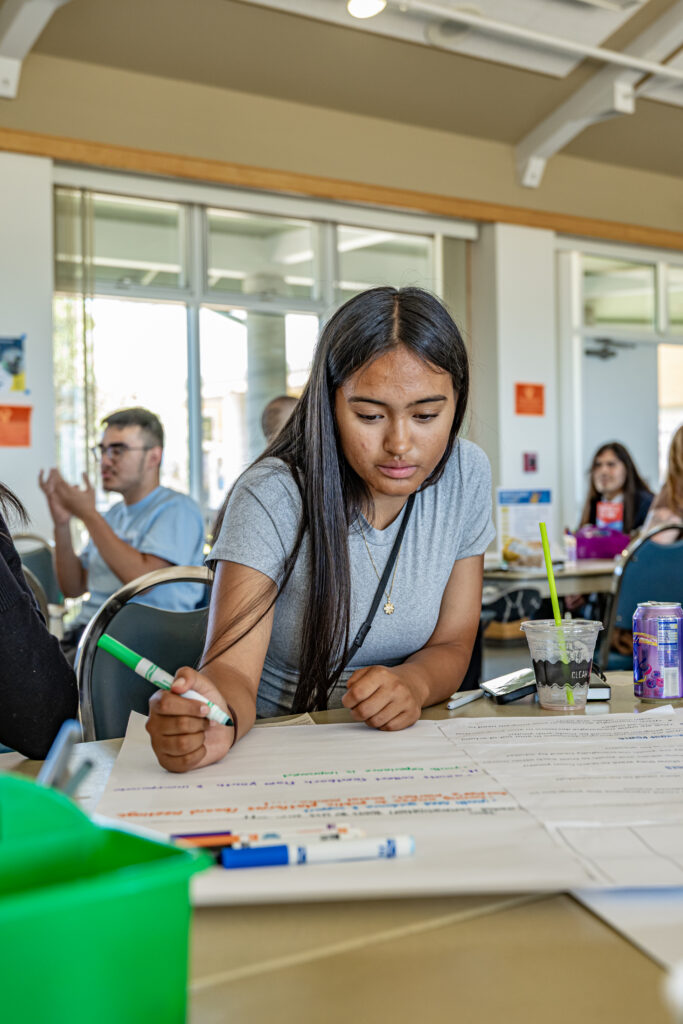 A young women writes on a poster board with a marker