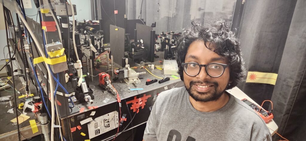 Student next to experimental setup in a lab