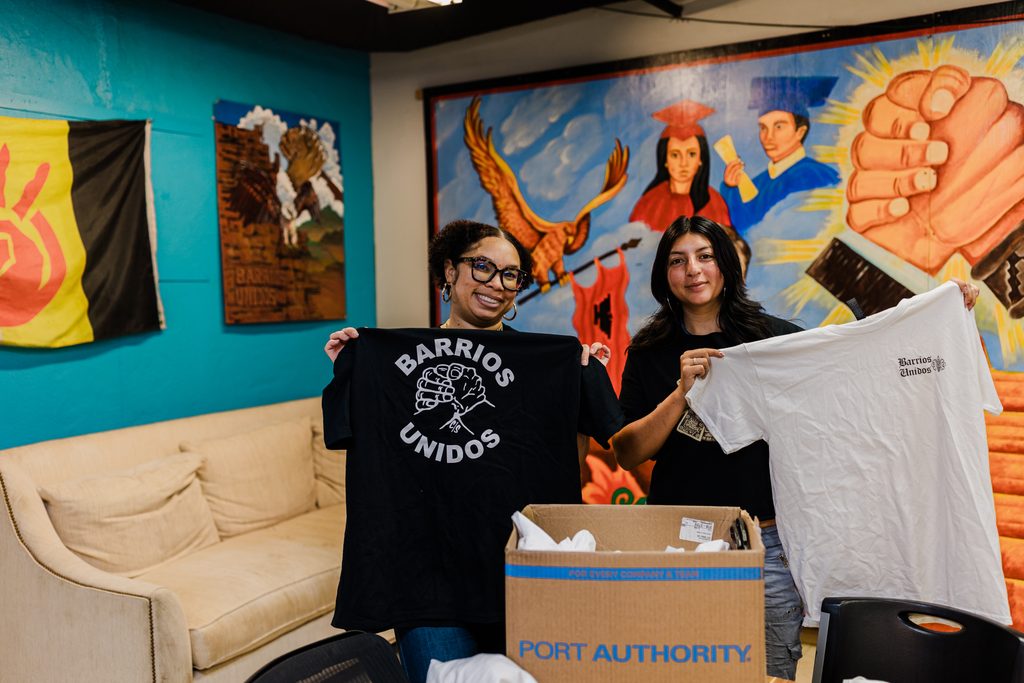 Cherre Bull and Maya Mendoza hold up Barrios Unidos t-shirts.