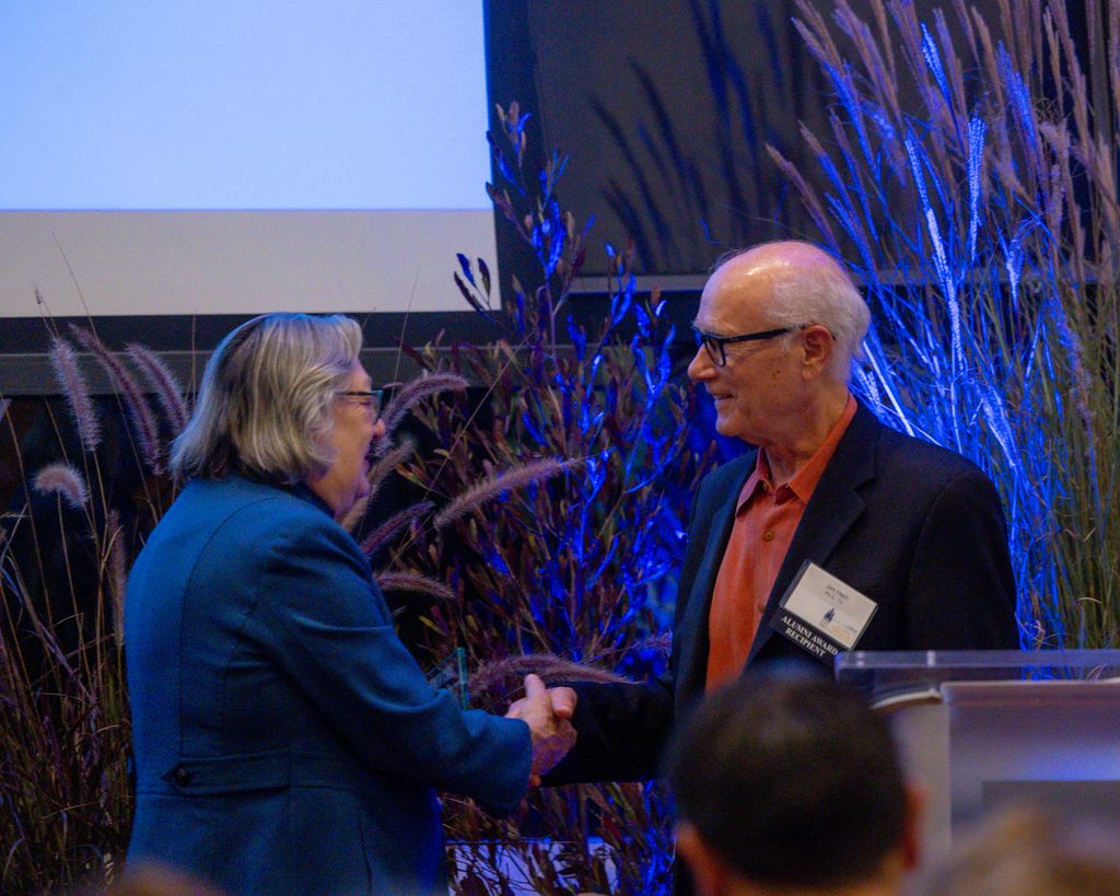 Chancellor Larive shakes hands with James Hein at the podium