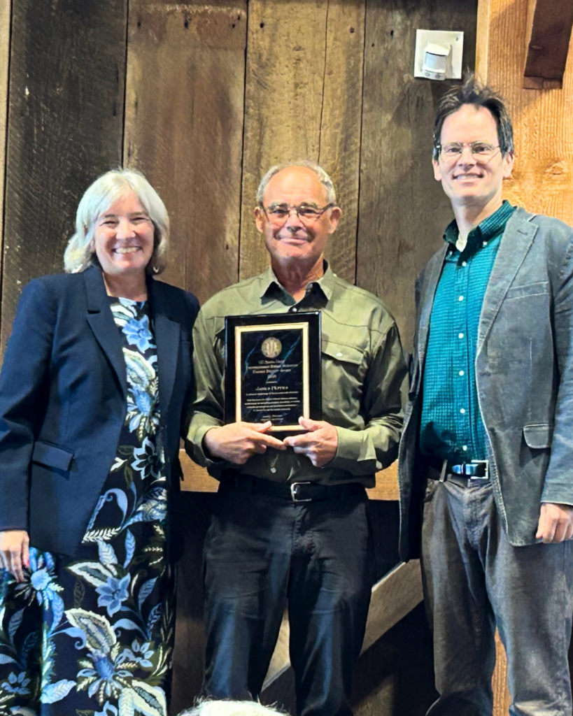 three people next to one another with center person holding a plaque
