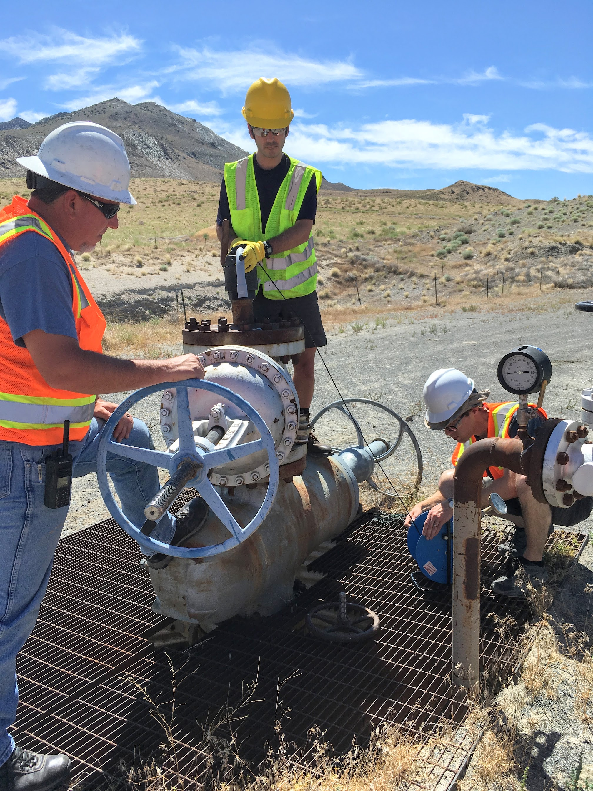 People in safety gear handling machinery at a geothermal observational well